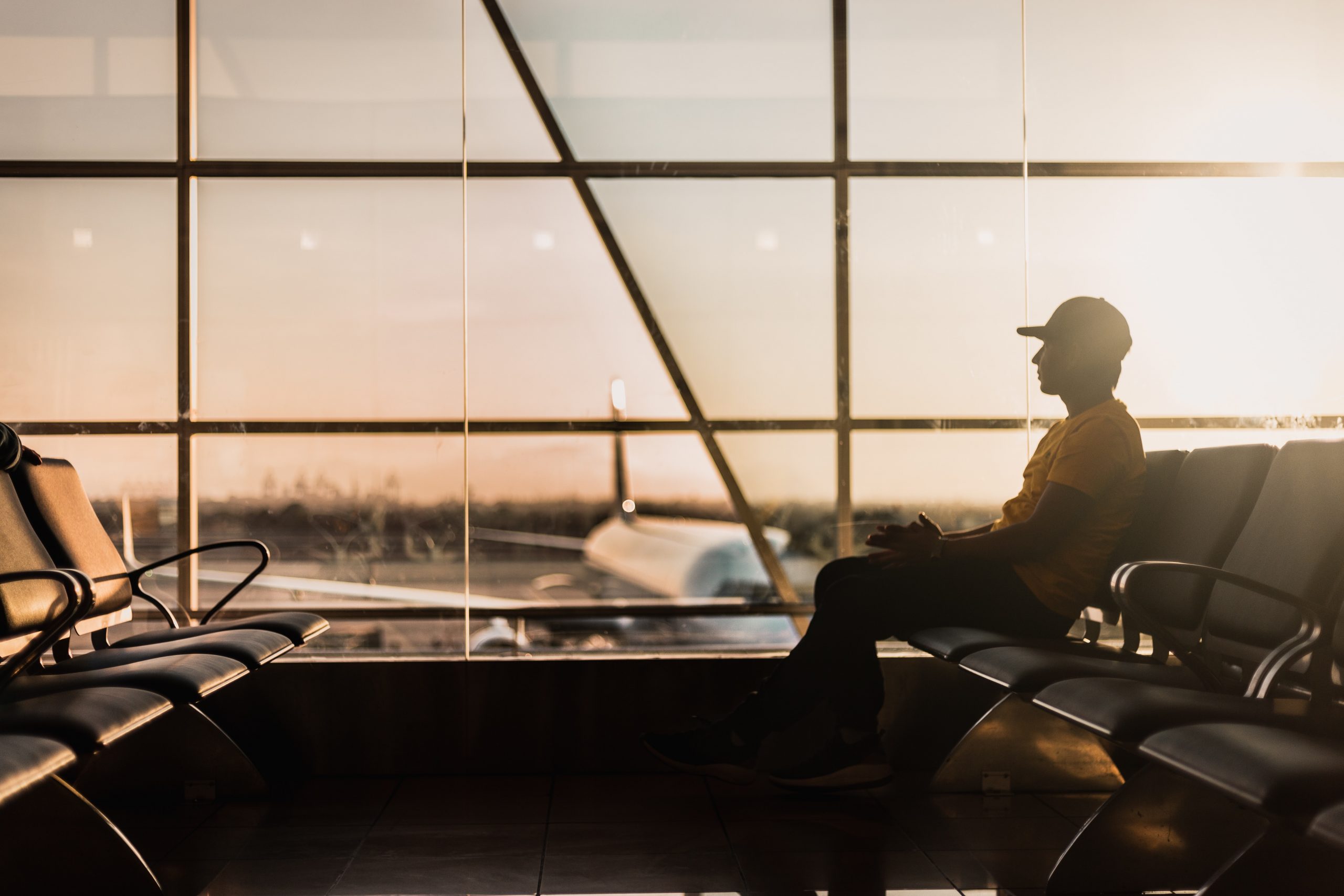 man sitting on gang chair near window - travel restrictions being lifted!